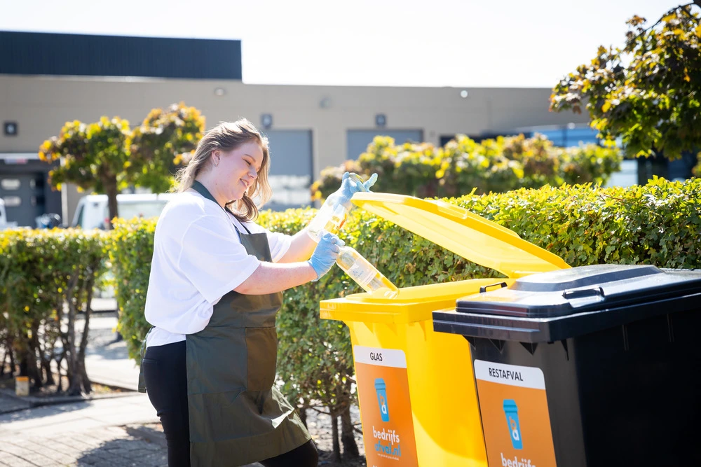Een glazen fles wordt weggegooid in de glascontainer