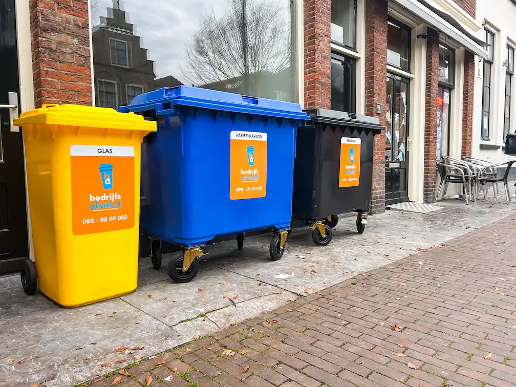 Een glas-, karton- en restafvalcontainer in een winkelstraat